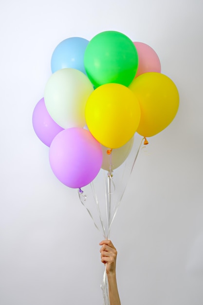 Mazzo di palloncini multicolori in mano di donna su sfondo bianco