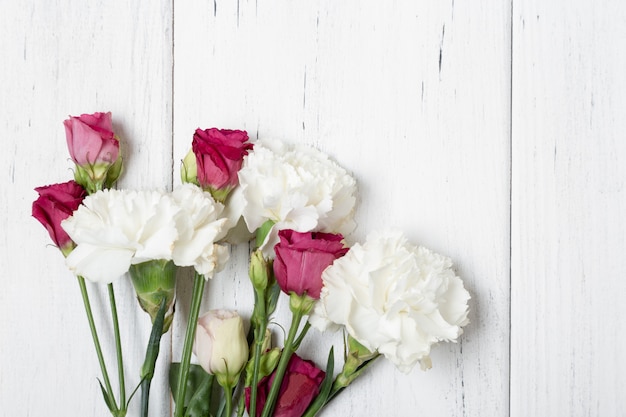 Mazzo di rose e garofani su backgeound in legno bianco