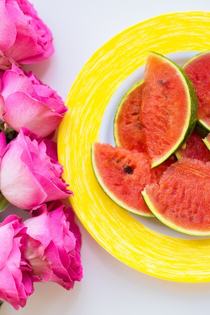 Mazzo di rose rosa sul tavolo con l'anguria