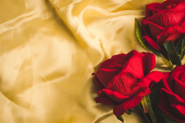 Mazzo di rose rosse su sfondo tessuto d&#39;oro. Spazio libero per il testo