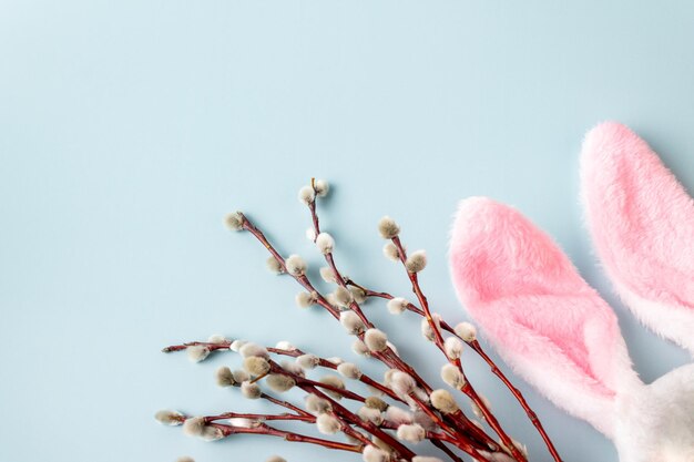 Mazzo di salice e orecchie di coniglietto di peluche su sfondo blu spazio copia