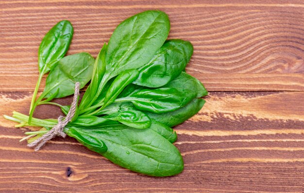 Mazzo di spinaci giovani, freschi e verdi sul fondo della tavola di legno