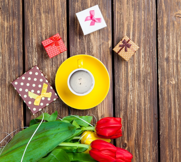 mazzo di tulipani, regali carini e tazza di caffè sul meraviglioso sfondo in legno marrone