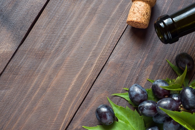 Mazzo di uva rossa e bianca, bottiglia di vino e sughero su legno