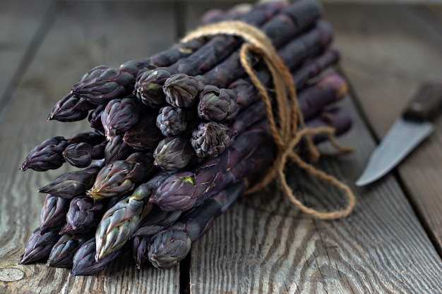 Mazzo fresco di asparagi porpora su un fondo di legno.