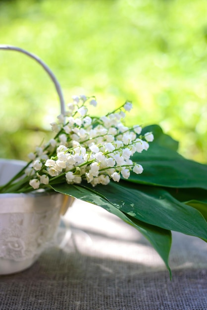 Mazzo primaverile di mughetti in un cesto decorativo bianco