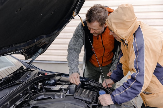 Meccanici automobilistici bianchi caucasici che lavorano in un'officina di riparazione auto Installazione della nuova batteria sotto il cofano