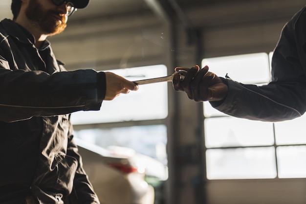 Meccanici automobilistici che si passano una chiave inglese