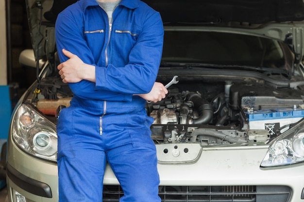 Meccanico appoggiato su auto con cappuccio aperto