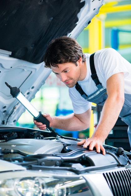 Meccanico auto che lavora in officina di servizio auto