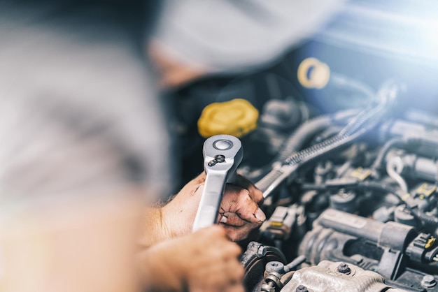 Meccanico auto fai da te che lavora in garage con chiave inglese