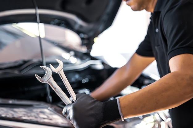 Meccanico automatico a mano in primo piano che utilizza la chiave per riparare il problema del motore dell'auto Concetti di controllo e ispezione, manutenzione e assistenza per la cura dell'auto