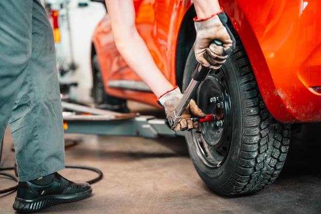 Meccanico automobilistico che cambia il pneumatico in lega della ruota Lavoro in officina Servizio auto Processo di controllo delle condizioni dei pneumatici sostituiti presso un centro di assistenza Industria automobilisticaxA