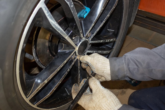 Meccanico automobilistico nel processo di sostituzione di pneumatici nuovi Riparazione dei freni dell'auto in garage