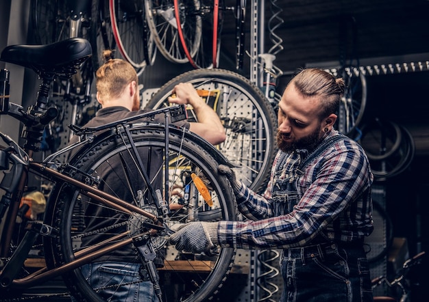 Meccanico barbuto che fa il manuale di servizio della ruota di bicicletta in un'officina.