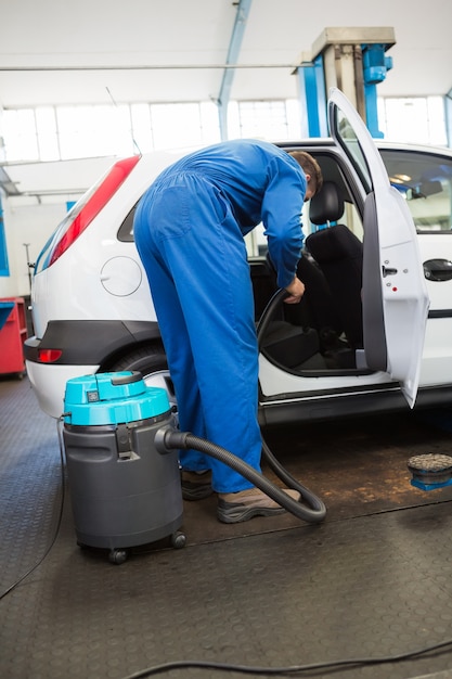 Meccanico che aspira l&#39;interno dell&#39;auto