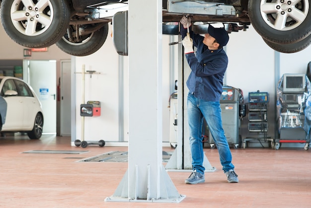 Meccanico che fissa un&#39;automobile sollevata