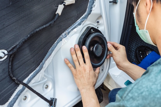 Meccanico che installa l'altoparlante sulla parte della portiera del veicolo in garage