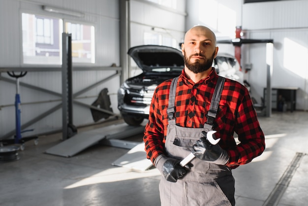 Meccanico che lavora e tiene la chiave dell'ordine di servizio per la manutenzione dell'auto presso l'officina