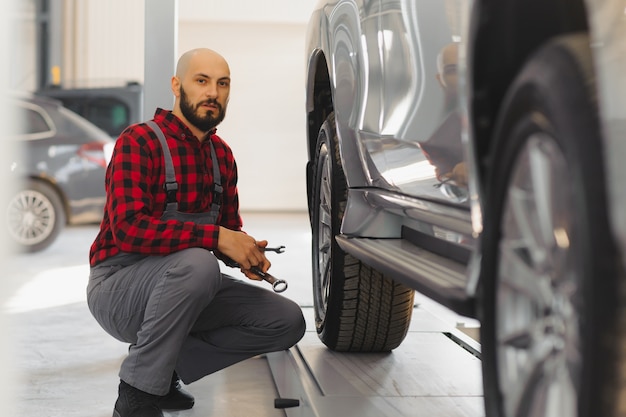 Meccanico che lavora e tiene la chiave dell'ordine di servizio per la manutenzione dell'auto presso l'officina