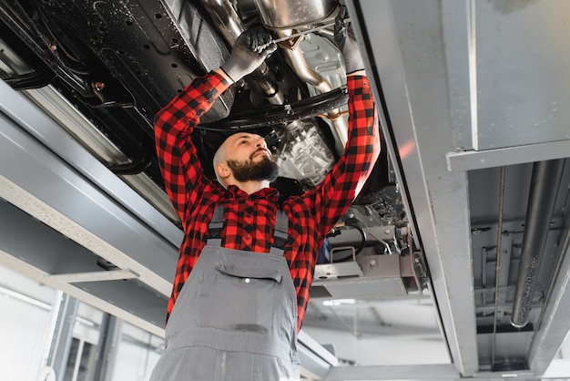 Meccanico che lavora sotto auto presso il garage di riparazione