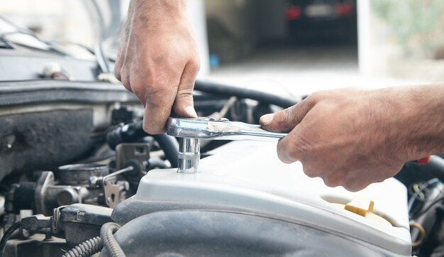 Meccanico che ripara auto con chiave a cricchetto.