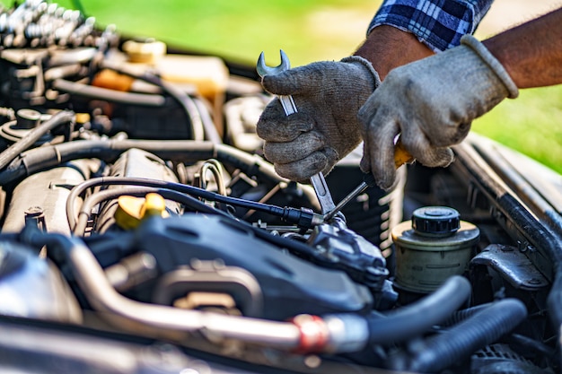 Meccanico che ripara un motore di automobile. Servizio di riparazione