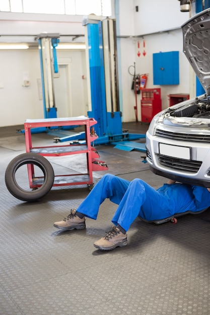 Meccanico che si trova e che lavora sotto l&#39;automobile