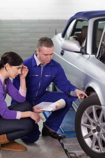 Meccanico che tocca la ruota dell&#39;auto mentre la guarda