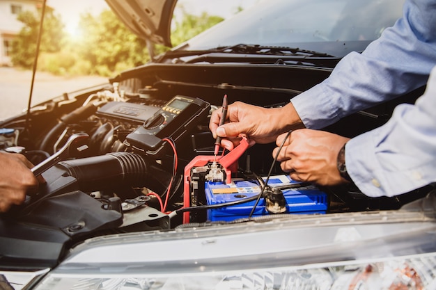 Meccanico che utilizza strumenti di misurazione per controllare la batteria dell'auto.