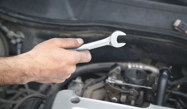 Meccanico con chiave in mano. Manutenzione dell'auto