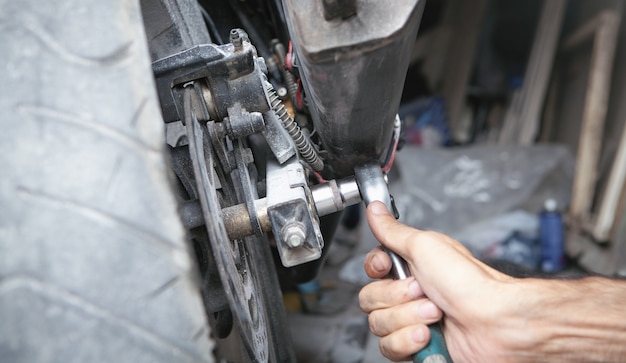 Meccanico con chiave inglese. Lavorare sulla moto in garage