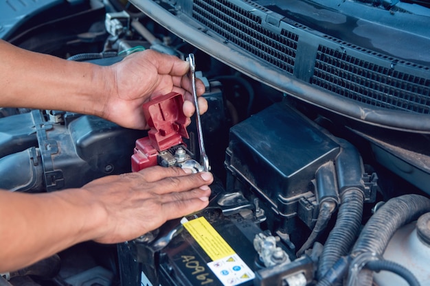 Meccanico di auto che lavora Installare la batteria con la chiave nel garage. Servizio di riparazione.