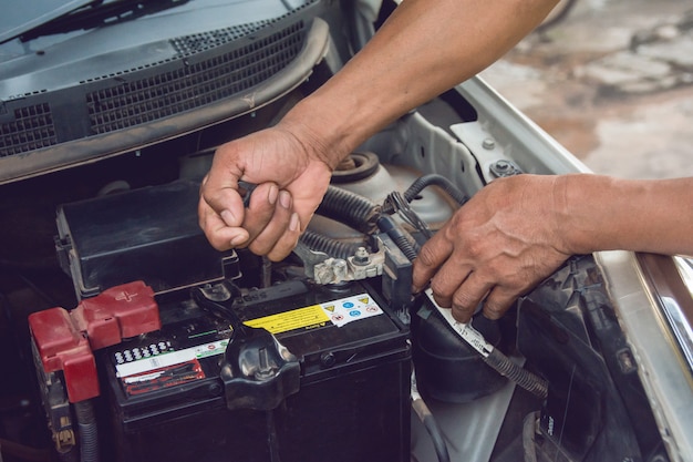 Meccanico di auto che lavora Installare la batteria con la chiave nel garage. Servizio di riparazione.