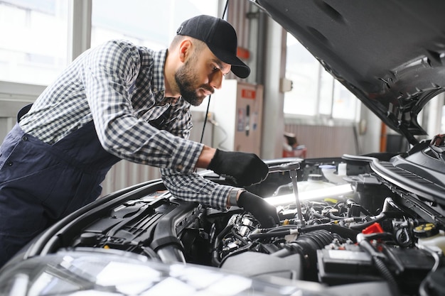 Meccanico di automobile bello è in posa in un servizio di auto