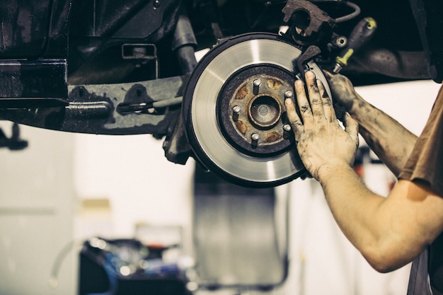 Meccanico di automobile che cambia i freni dell'auto, concetto di trasporto