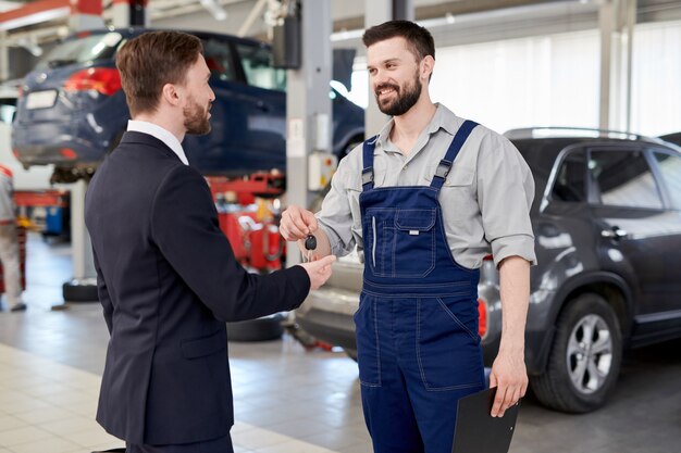 Meccanico di automobile che dà le chiavi all'uomo d'affari