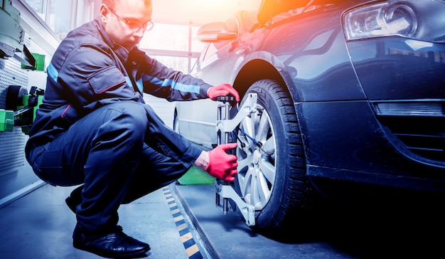 Meccanico di automobile che installa sensore durante la regolazione delle sospensioni.