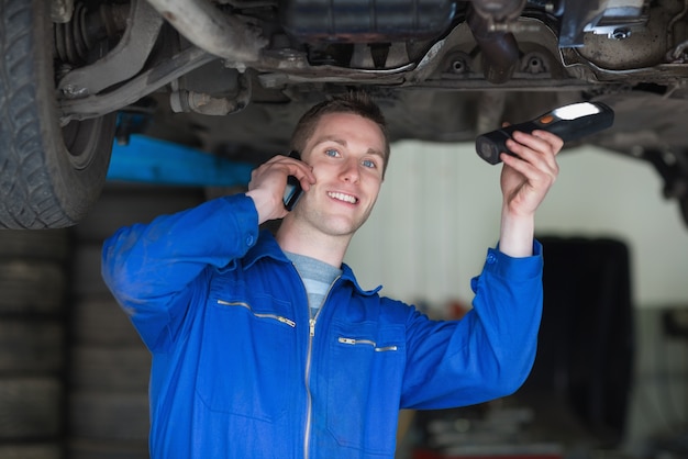 Meccanico di automobile che per mezzo del telefono cellulare