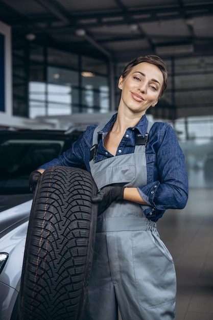 Meccanico di automobile della donna che cambia le gomme al servizio dell'automobile