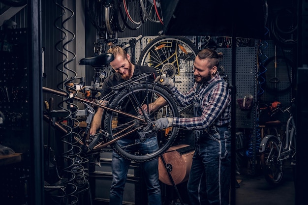 Meccanico di biciclette in un'officina con parti di biciclette e ruota su uno sfondo.