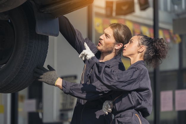 Meccanico esaminando la parte inferiore al servizio di auto, servizio di riparazioni auto.