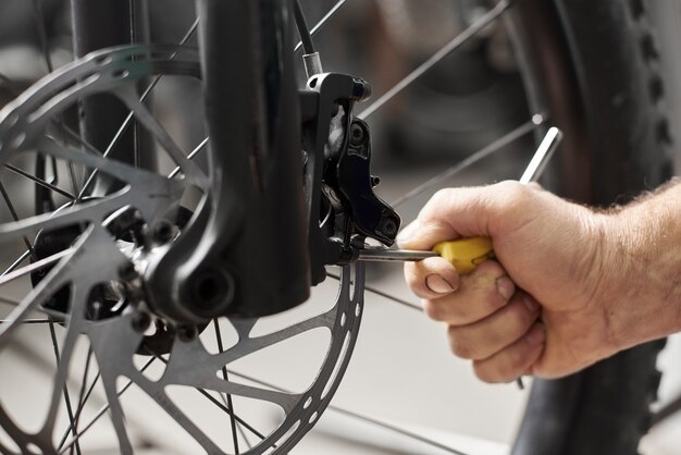 Meccanico maschio che fa servizio nel negozio di riparazione di biciclette utilizzando strumenti