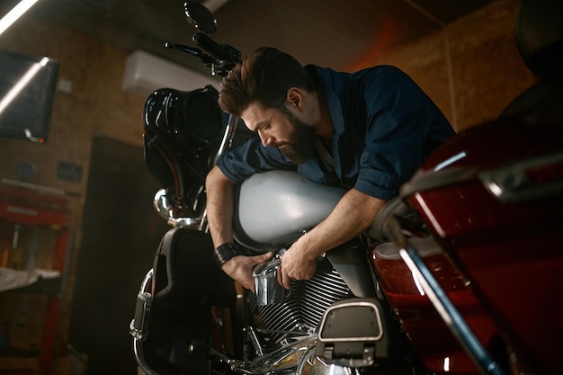 Meccanico maschio che lavora in garage e ripara motociclette personalizzate