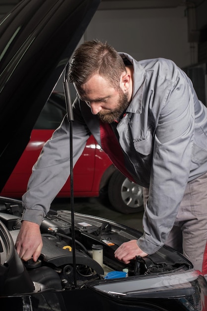 Meccanico maschio che ripara l'auto in un negozio di riparazione automobilistica