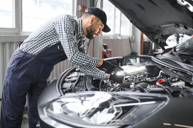 Meccanico professionista sta lavorando su un'auto in un servizio di auto