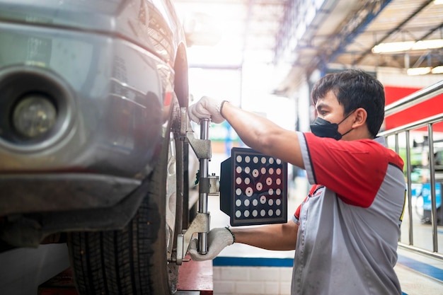 Meccanico professionista vicino al centro della ruota Allineamento ruote montato su ogni pneumatico per centro di guida Allineamento ruote in garage