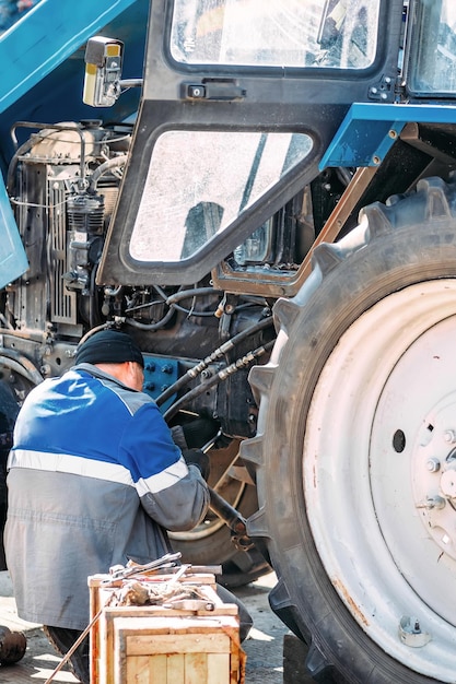 Meccanico riparazione del motore di trattore o di attrezzature pesanti agricoltore ispeziona e diagnostica agricola