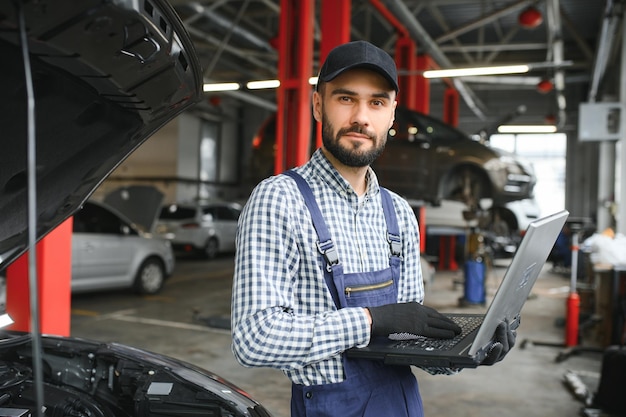 Meccanico sorridente che usa un portatile al garage di riparazione