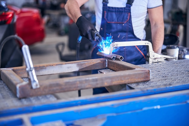 Mechanic using welding torch in auto repair shop